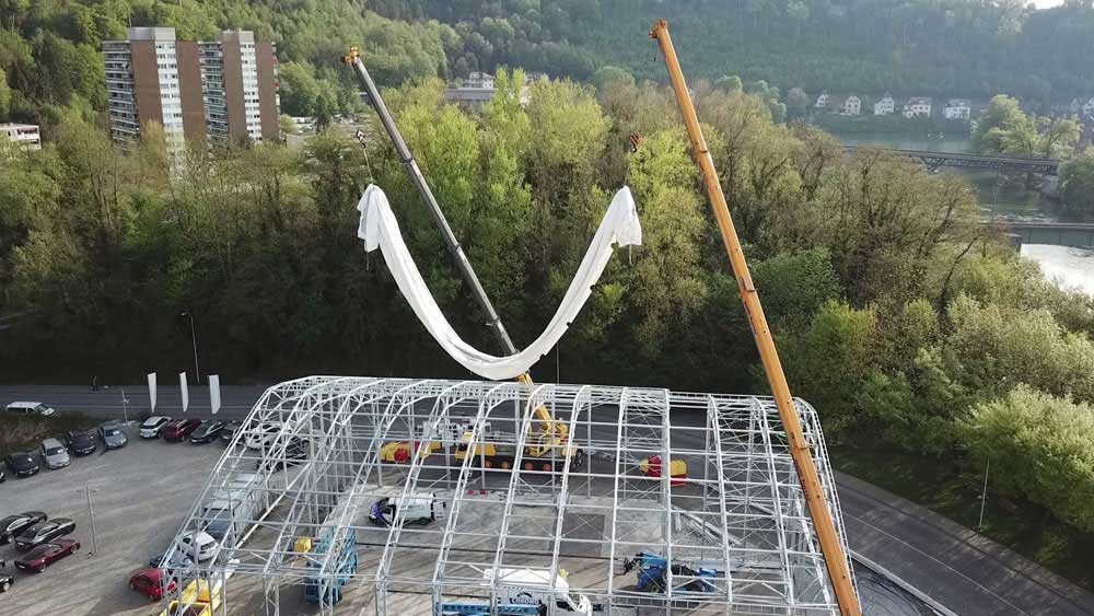Verlegung einer PVC-Membran auf dem Dach einer Zelthalle mithilfe von Kränen