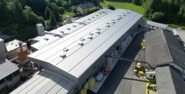Luftaufnahme einer grossen Fertighalle mit mehreren Hallenschiffen und Produktionsanlagen.