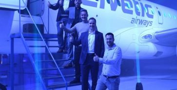 Team des Unternehmens steht bei der Eröffnung im Hangar in Brnik neben einem Flugzeug.