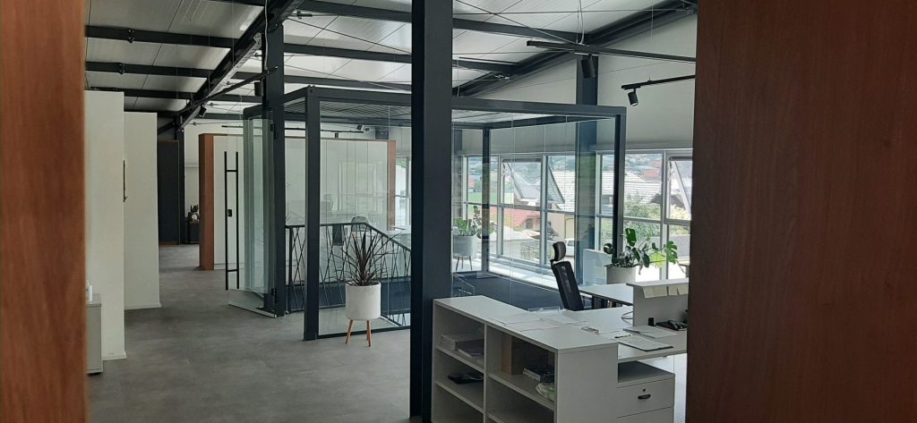 Innenansicht moderner Büroflächen in einer Bürohalle mit Glaswänden und Arbeitsplätzen