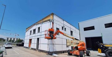 Hubarbeitsbühne neben einem Industriegebäude während der Fassadenarbeiten.